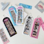 étui photos PVC semi rigide vertical photomaton quatre fentes fenêtre transparente chaînette métal motifs étoiles brillant coloris pastel